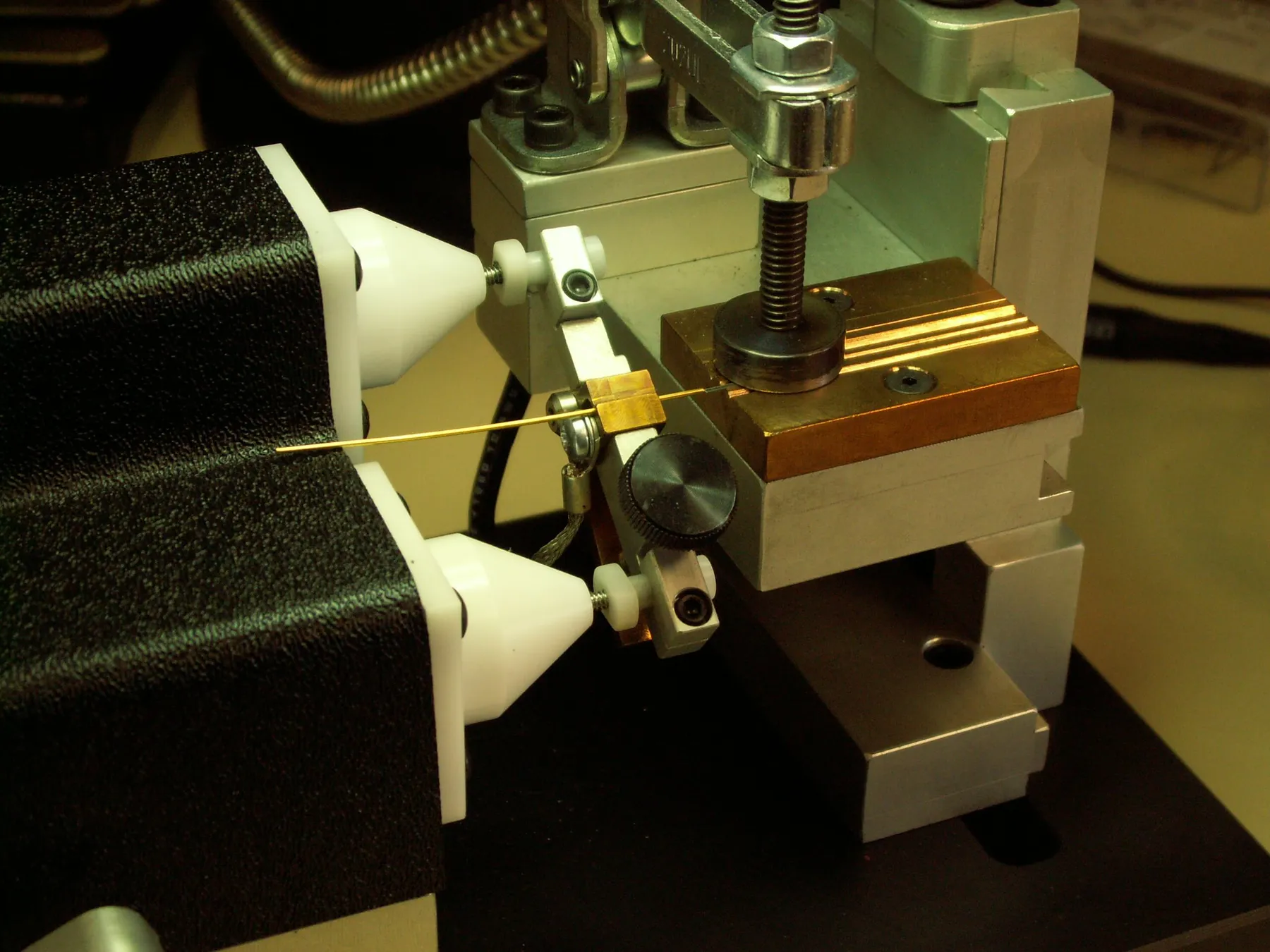 Thin wire lead held between the electrode cones and clamp of the bench fixture