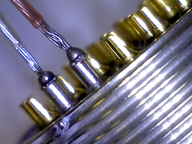 Close-up of gold-colored pins with wires joined to a ribbed metal body