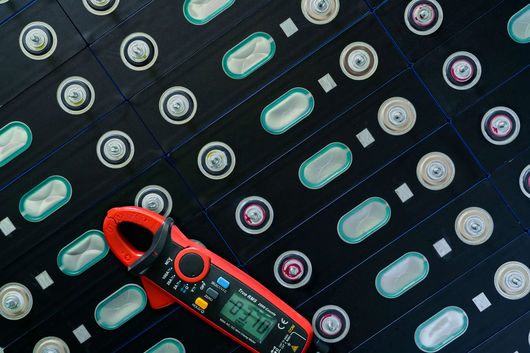 Rows of battery cells with a clamp meter on top