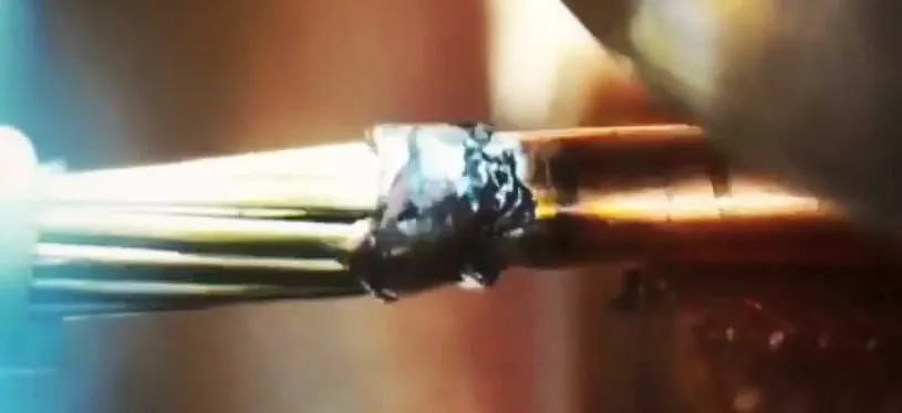Stranded wire end with a dark weld ball, magnified