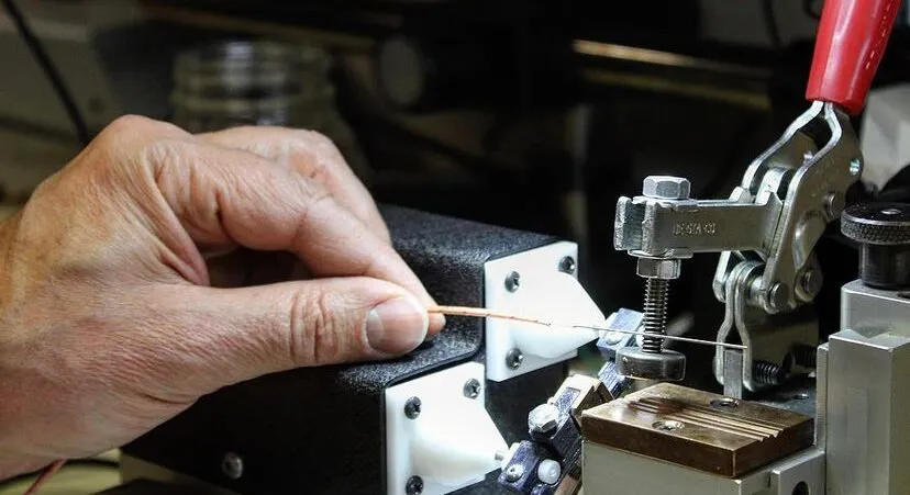 Hand placing a thin wire into the bench fixture electrode holders