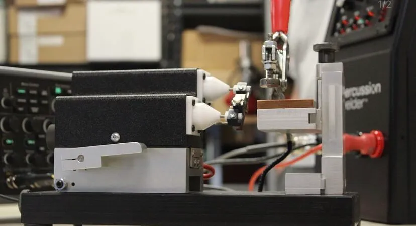 Side view of the bench fixture with toggle clamp beside the percussion welder