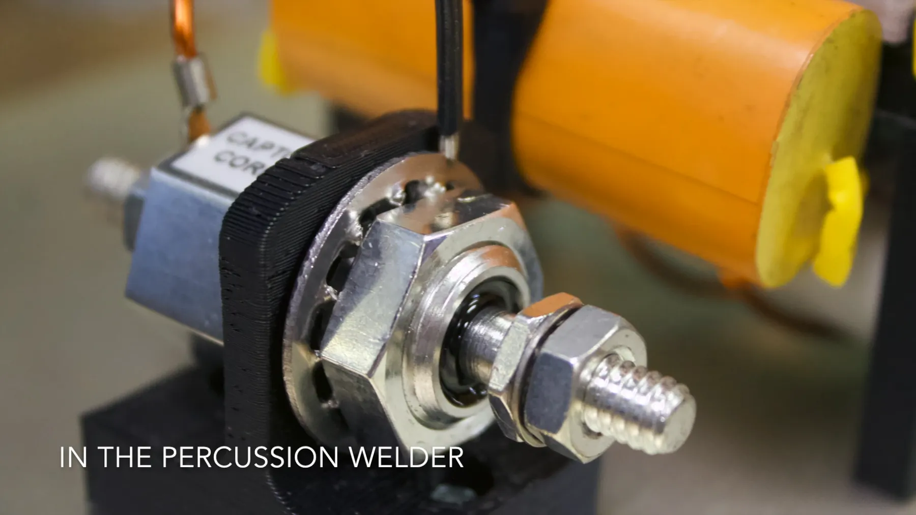 Small actuator with a nut and bolt, captioned In the Percussion Welder